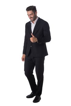 Full length portrait of young handsome business man in black suit smiling and showing thumbs up studio isolated on white background