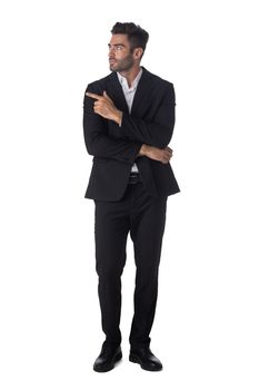 Full length portrait of young handsome business man in black suit pointing showing copy space studio isolated on white background