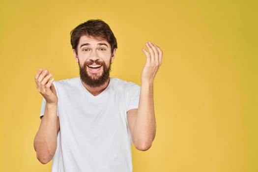 Bearded man white t-shirt emotions gestures with hands fun yellow background. High quality photo