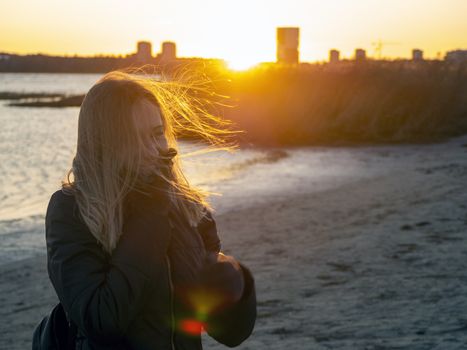 Silhouette of a lonely woman watching sunset in autumn. downtown buildings silhouettes. Nature Orange sea sunset in the city landscape beautiful landscape of Tallinn skyline Panoramic view on beach