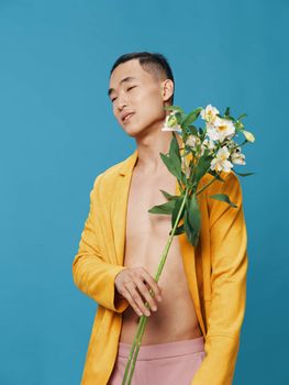 young man in a yellow coat and white flowers blue background. High quality photo