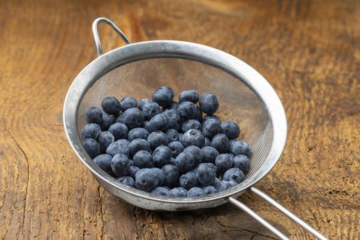 blue berries in a sieve on wood