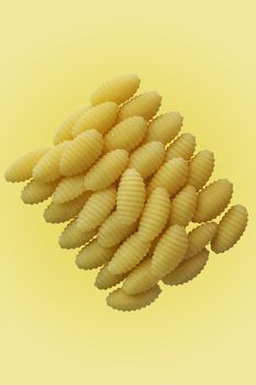 pasta dumplings of durum wheat semolina also called malloreddus or gnocchetti sardi , Italian pasta , studio shot , yellow  background