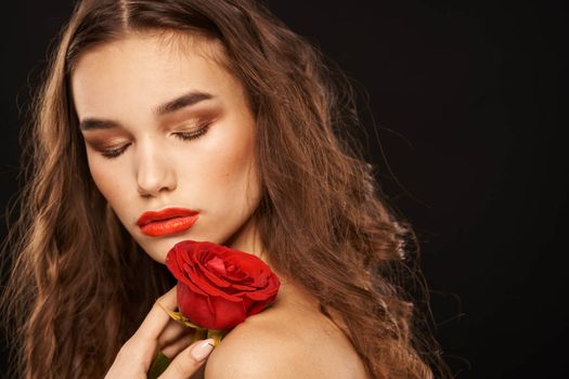 woman with a red rose on a dark background long hair makeup red lips. High quality photo