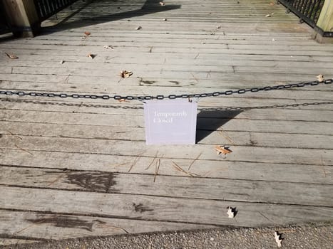 temporarily closed sign with chain and wooden boardwalk