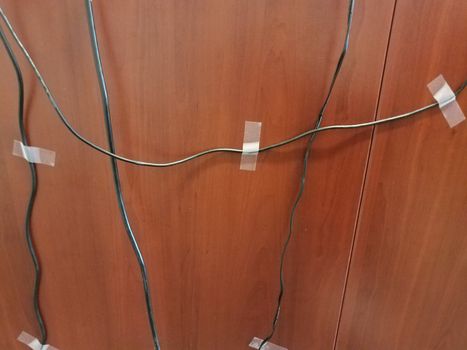 computer wires or cables taped to a brown wood desk