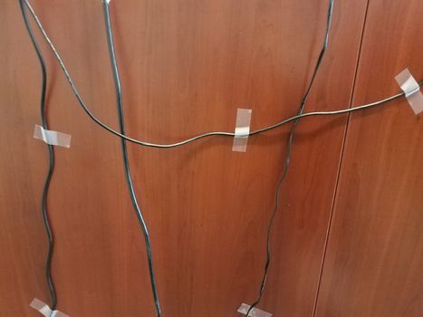 computer wires or cables taped to a brown wood desk