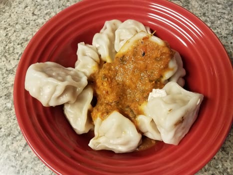 asian dumplings and spicy red sauce in bowl