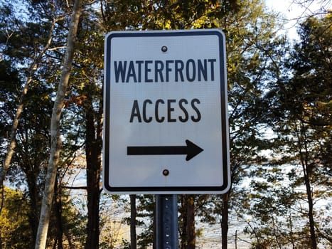 waterfront access sign with arrow and trees in forest