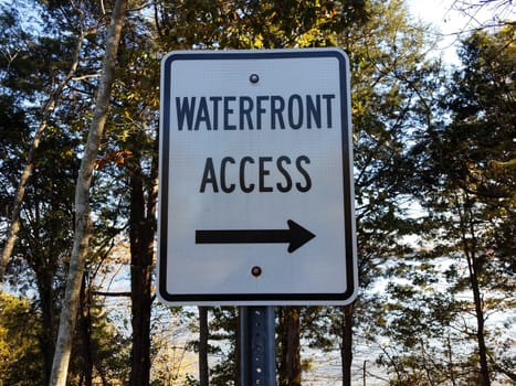 waterfront access sign with arrow and trees in forest