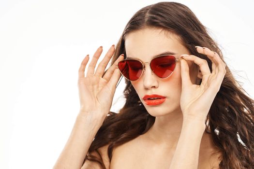 Portrait of brunette woman in sunglasses naked shoulders light background. High quality photo