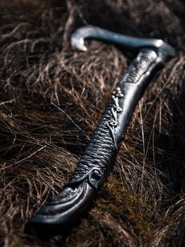 Close up look at the ancient Scandinavian vikings axe at the summer sunset on the deep grass