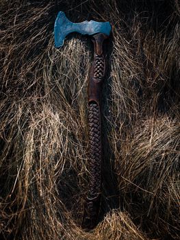 Close up look at the ancient Scandinavian vikings axe at the summer sunset on the deep grass