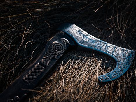 Close up look at the ancient Scandinavian vikings axe at the summer sunset on the deep grass