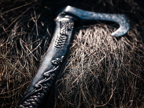 Close up look at the ancient Scandinavian vikings axe at the summer sunset on the deep grass