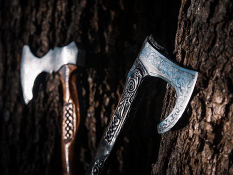 Close up look at the ancient Scandinavian vikings axe at the summer sunset on the deep grass