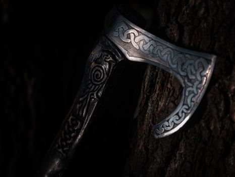 Close up look at the ancient Scandinavian vikings axe at the summer sunset on the deep grass