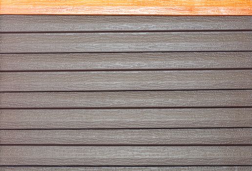 Brown vinyl siding with imitation wood grain. Vinyl texture and siding background in exterior wall surface.