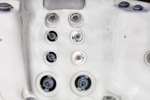 Large and small hydromassage nozzles with control buttons in a spa jacuzzi, close-up.