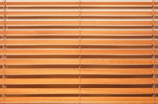 Background and texture of light brown, wooden blinds with wide slats in a horizontal line.