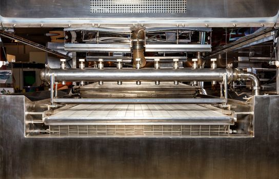 Spraying mechanism made of stainless steel on the conveyor of a production line in the food industry, copy space.