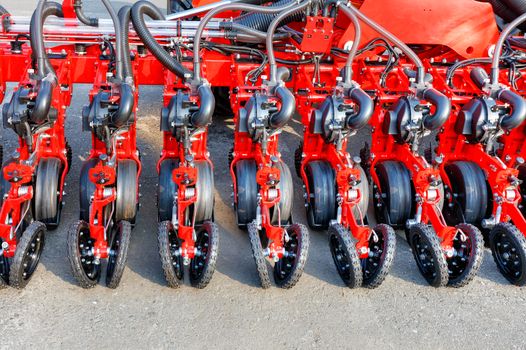 Red modern multi-row seeder, wheels, distribution pipes and working mechanisms of pneumatic agricultural seeder, copy space.