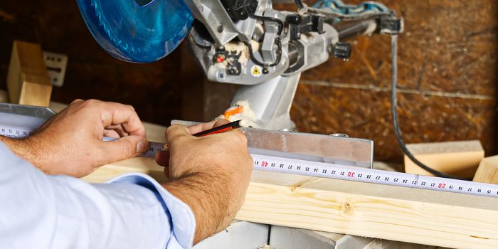 Carpenter work concept. Carpenter work with circular saw for cutting wood bar, the man sawed bars, construction and home renovation.