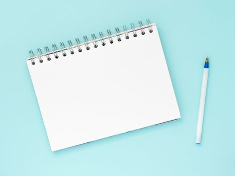 Top view of blank note paper with pen on blue wood table for background