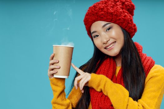 Woman with a red scarf and in a hat hot coffee warming drink blue background cool