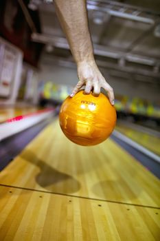 Bowling ball orange at hand of man background bowling alley