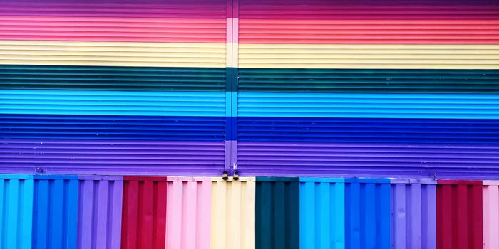 Striped wall blinds painted in various colors of the rainbow. Background texture closeup.