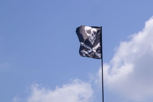 pirate flag develops in the wind, skull with bones, Jolly Roger,the symbol of the robbery