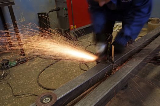 Grinding metal.Grinding wheel. Locksmith cleans iron corner after welding in workshop. Sparks are flying.