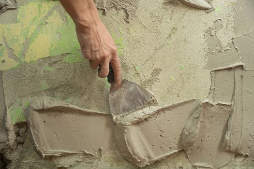 A worker plasters the wall with a spatula and applies a cement mix solution. The repairman lays the plaster on the drywall. Handyman repairs home. Laborer restore dwelling. Specialist covers up cracks