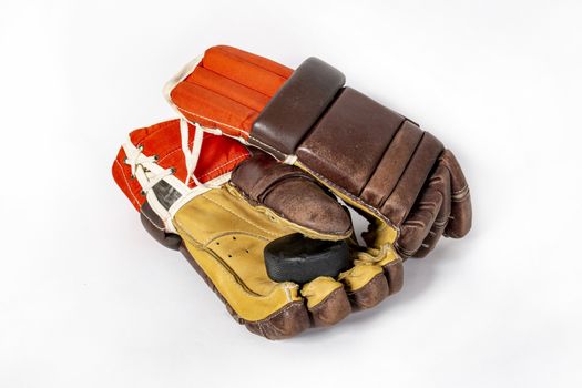 Old red hockey gloves for goalkeeper. Isolated over white background. Hockey puck. The concept of the game of hockey and hockey sport.