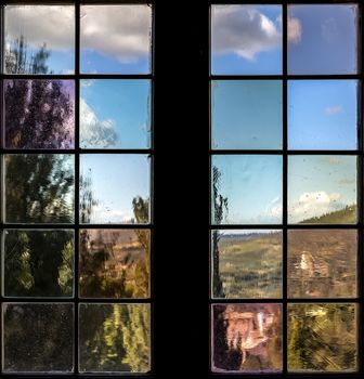 A window with multi-colored glass that overlooks a park or garden. Outside the window you can see a beautiful landscape. Old wooden window with shutters