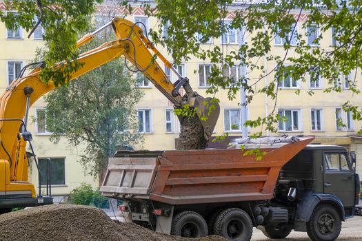 a digger scoops a bucket of gravel