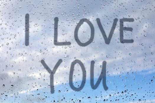 I love you - inscription with a finger on the window pane. There are raindrops on the glass.