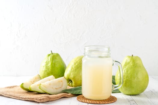 Delicious beautiful guava fruit with fresh juice set isolated on bright white wooden table background, close up.