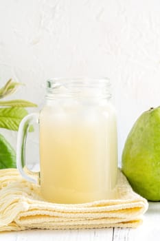 Delicious beautiful guava fruit with fresh juice set isolated on bright white wooden table background, close up.