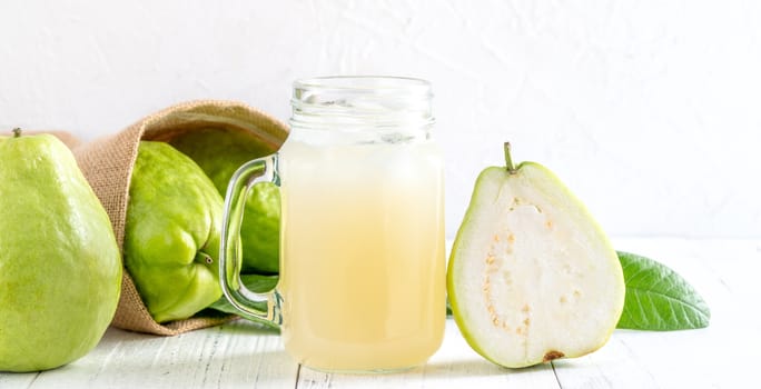 Delicious beautiful guava fruit with fresh juice set isolated on bright white wooden table background, close up.