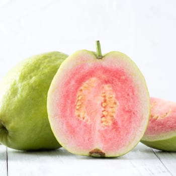 Top view, flat lay of delicious beautiful Red guava with fresh green leaves isolated on white table background, studio overhead table shot with copy space.