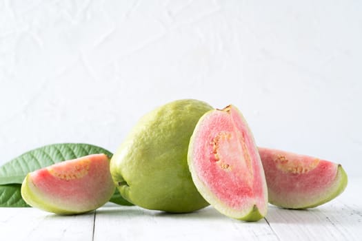 Top view, flat lay of delicious beautiful Red guava with fresh green leaves isolated on white table background, studio overhead table shot with copy space.