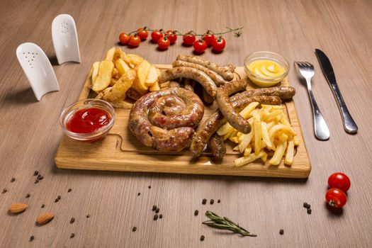 Set of grilled sausages a wooden board hunting sausages, pork sausages, homemade sausage, french fries, potato slices, tar-tar, barbecue, mustard,