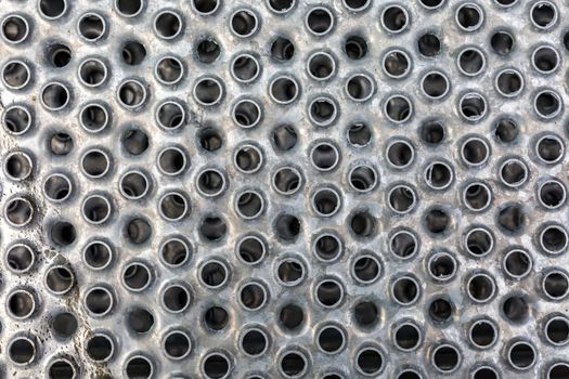 Iron sheet of gray color with round holes - background texture closeup.