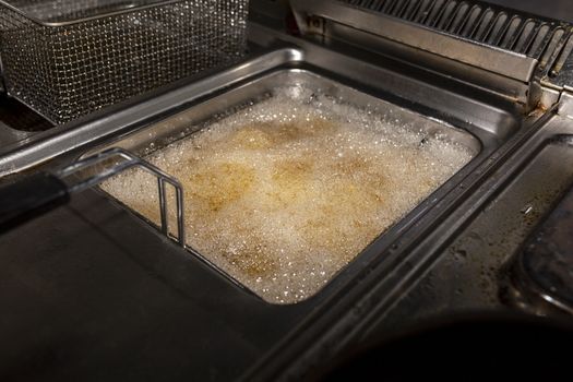 Deep fryer with boiling oil on restaurant kitchen
