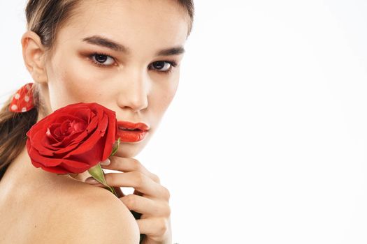 Beautiful woman with red rose near face makeup naked shoulders portrait. High quality photo