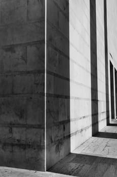 Shadows of a columns row cast on a building facade ,black and white photo ,geometic shape ,vertical composition ,wide angle lens ,