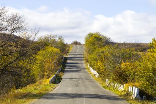 Empty highway and road in Georgia, autumn tree and plants and blue cloudy sky