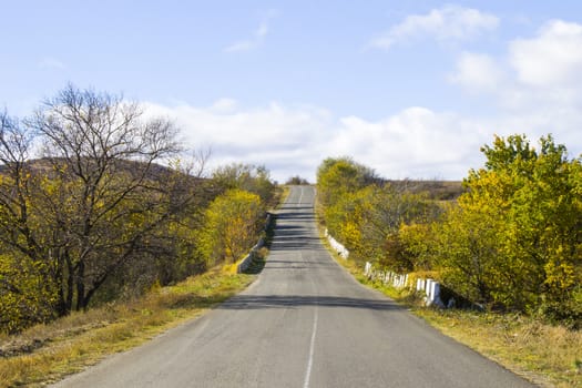 Empty highway and road in Georgia, autumn tree and plants and blue cloudy sky